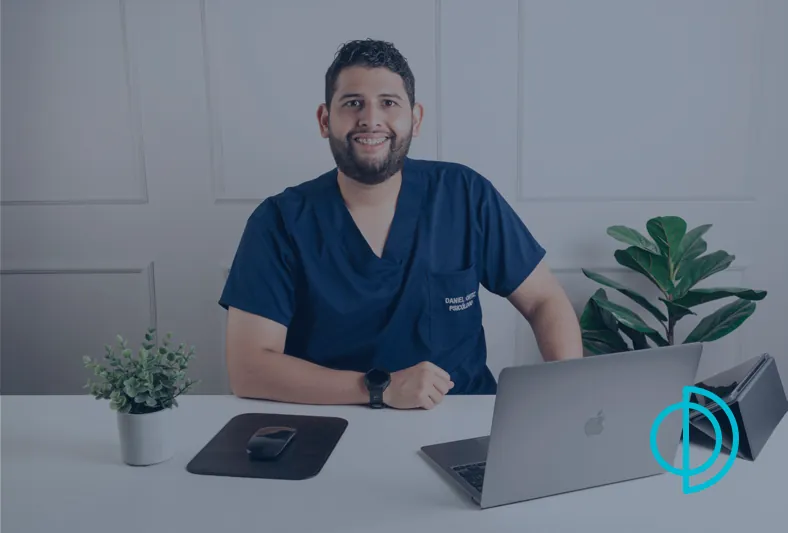 Daniel Ortiz, psicólogo en Cúcuta, sonriendo sentado frente a su escritorio con un portátil