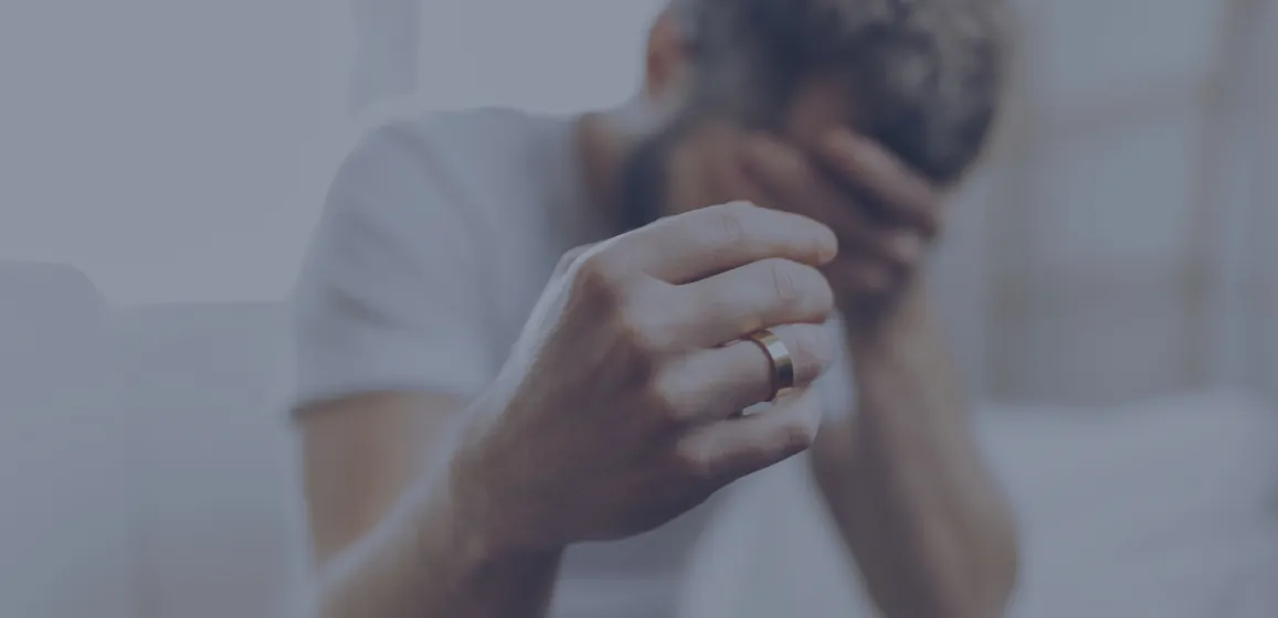 Hombre con anillo de matrimonio que se cubre el rostro por angustia y tristeza