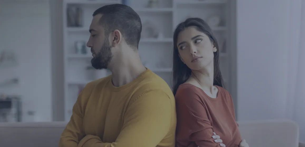 Pareja sentada espalda con espalda tras una discusión, motivo frecuente de consulta psicológica